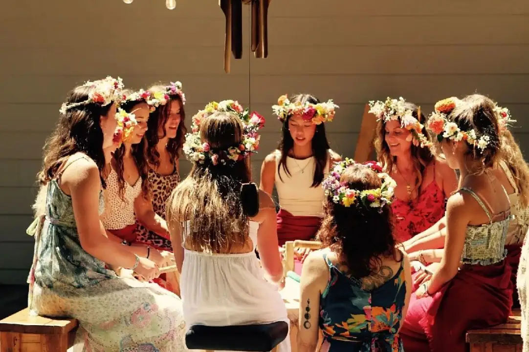 The 13 Moons circle seated together, wearing flower crowns