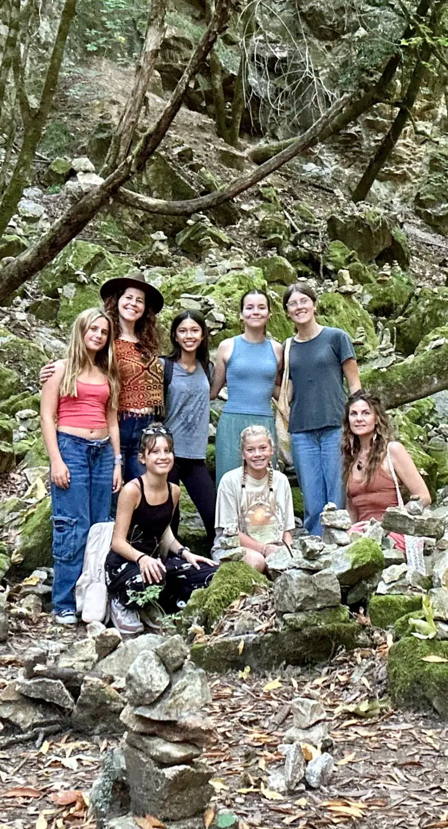 Girls and mentors among mossy stones and cairns in the forest